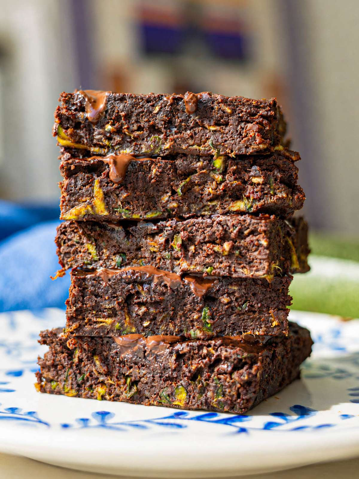 Stack of healthy zucchini brownies with melted chocolate pieces.