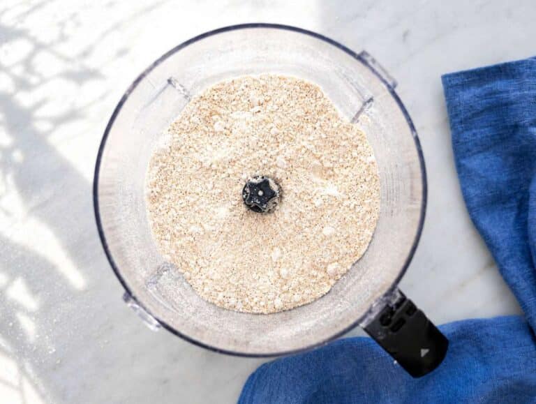 Step 1 Ground oats blended in food processor on marble countertop near natural window light.