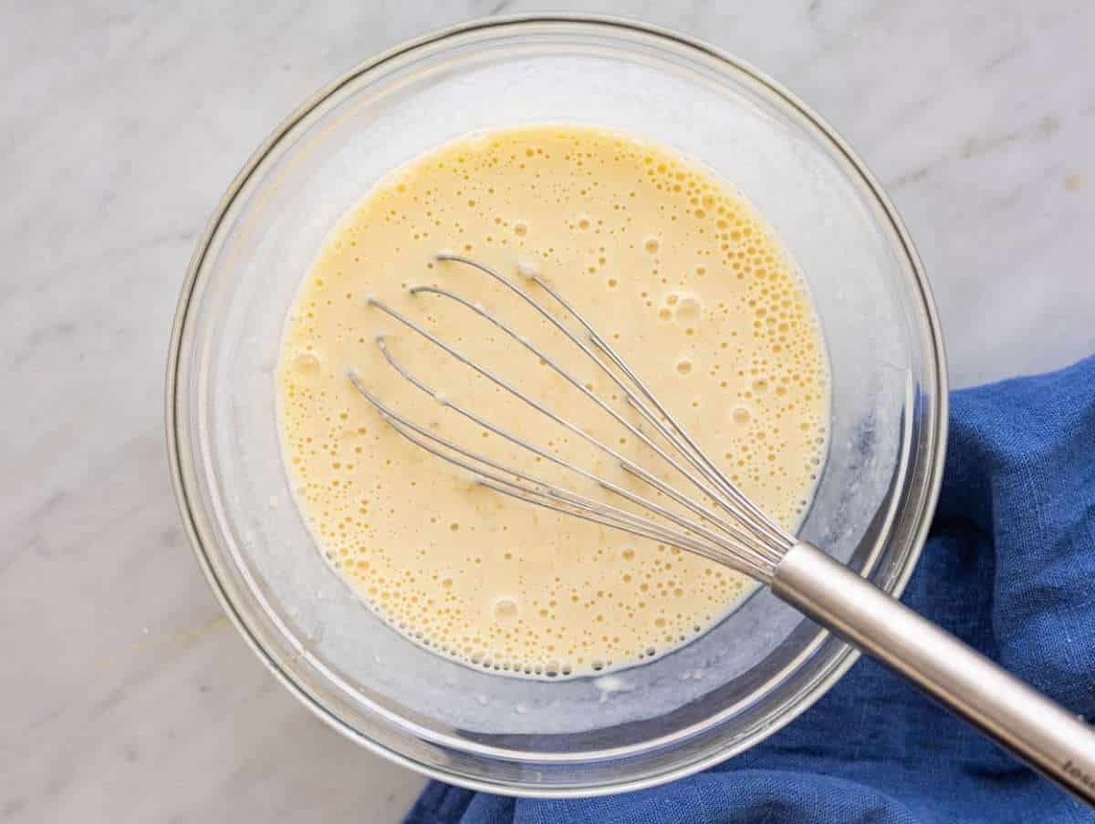 Step 1 Mashed bananas and yogurt being whisked together in a large bowl.