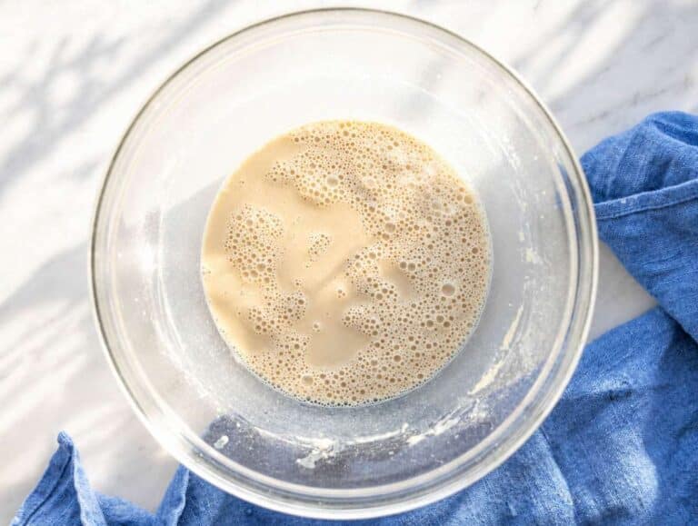 Step 1 Milk and protein powder being whisked together in bowl on marble surface.