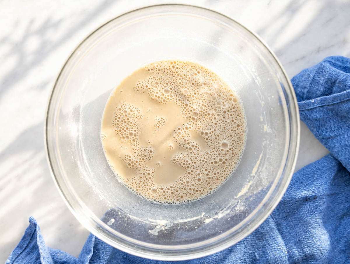 Step 1 Milk and protein powder being whisked together in bowl on marble surface.