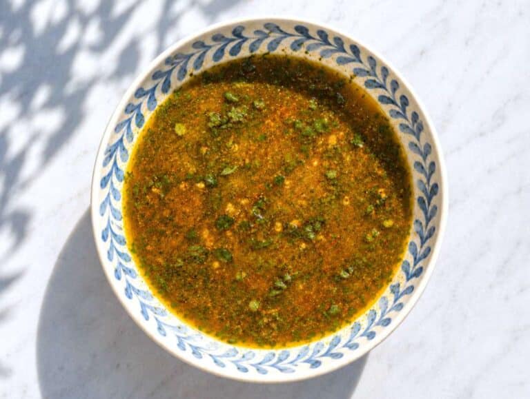 Step 1 Olive oil lime dressing with cilantro and spices whisked in small bowl on marble countertop.