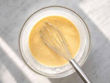 Step 2 Mashed bananas mixed with Greek yogurt, eggs, and protein powder in a glass bowl.