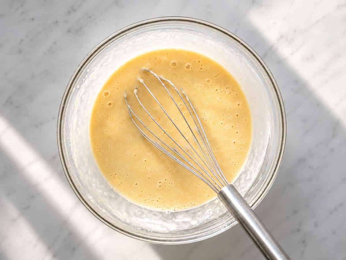 Step 2 Mashed bananas mixed with Greek yogurt, eggs, and protein powder in a glass bowl.