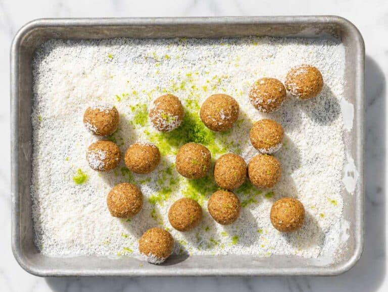 Step 2 energy balls ready to roll in shredded coconut on a baking tray