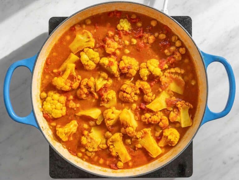 Step 3 Cauliflower and chickpeas simmering in tomato curry sauce in a large skillet.