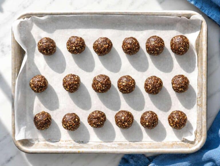 Step 4 Shaped date energy balls on a parchment-lined baking sheet.