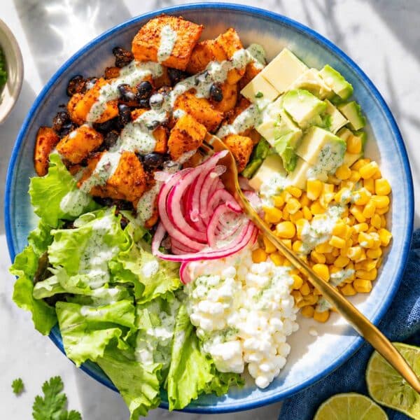 Sweet potato black bean bowl served with fresh toppings on a white marble table.