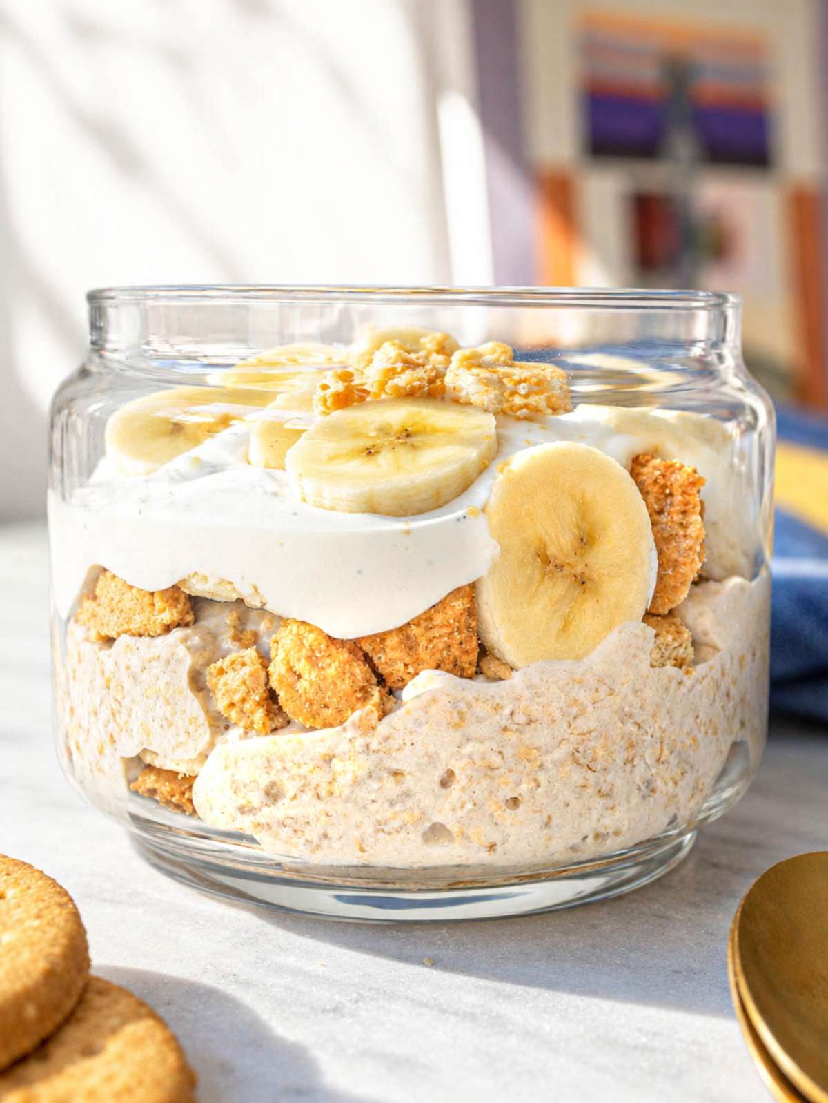 Banana pudding overnight oats topped with banana slices and crushed biscuits.
