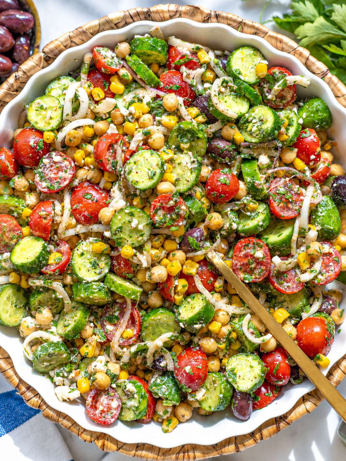 Bowl of chimichurri chickpea salad with feta, tomatoes, cucumber, and fresh parsley.