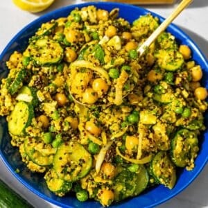 Bowl of turmeric chickpea salad with lemon and parsley on marble surface.