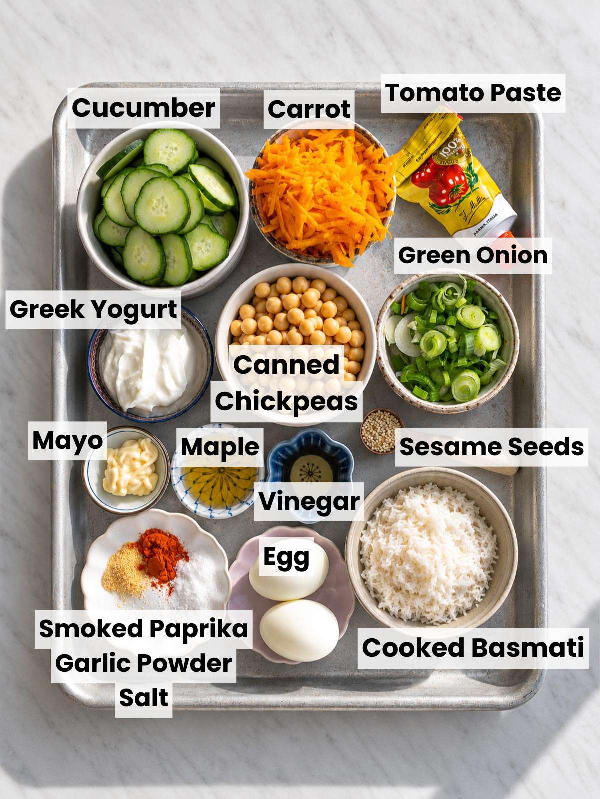Chickpeas, yogurt, rice, eggs, and vegetables arranged on marble countertop.