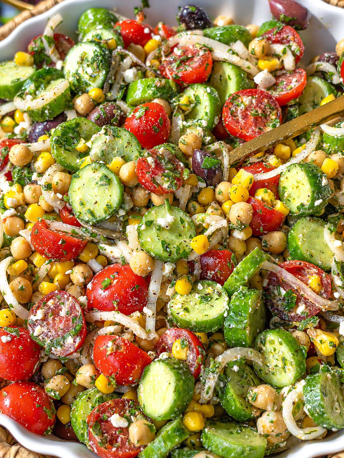 Close-up of marinated chickpeas coated in chimichurri with feta and juicy tomatoes.
