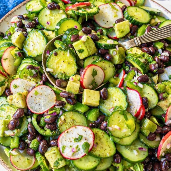 Colorful Mexican cucumber salad served on a plate with spoon.