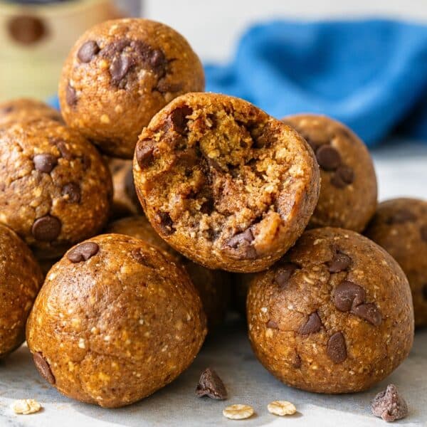 Cookie dough energy balls with a bite on white marble.