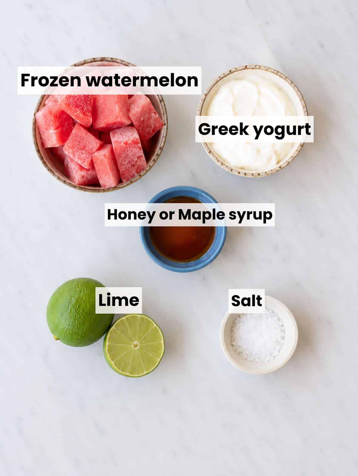 Frozen watermelon cubes, Greek yogurt, lime, honey, and salt on marble table.