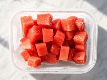 Frozen watermelon cubes in a glass container.