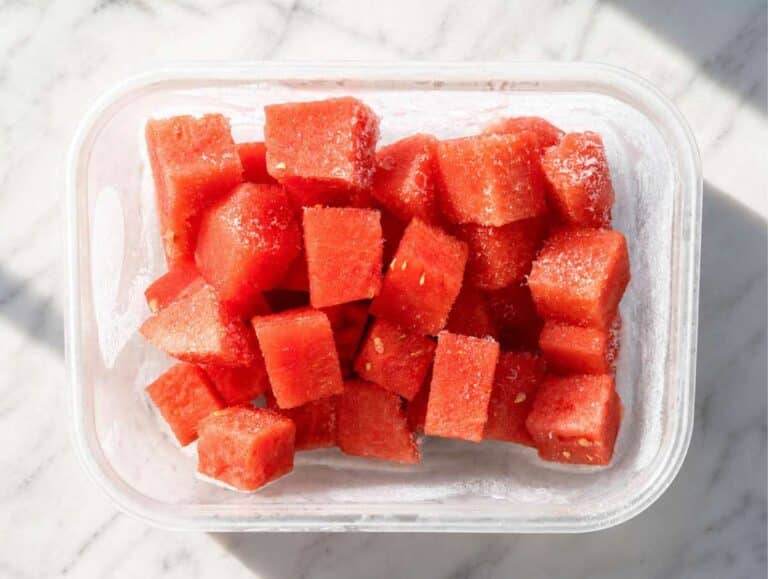 Frozen watermelon cubes in a glass container.