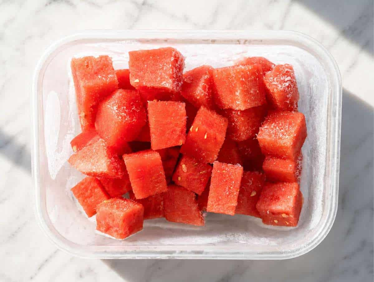 Frozen watermelon cubes in a glass container.
