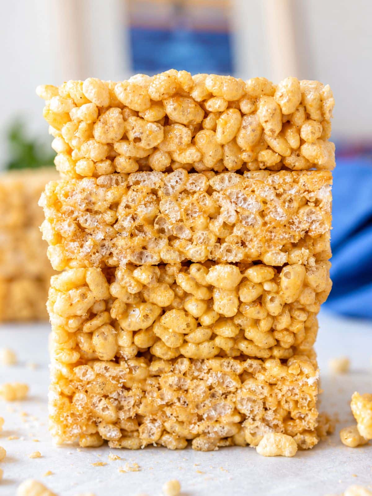 Healthy Rice Krispie Treats stacked on white marble in bright natural window light.