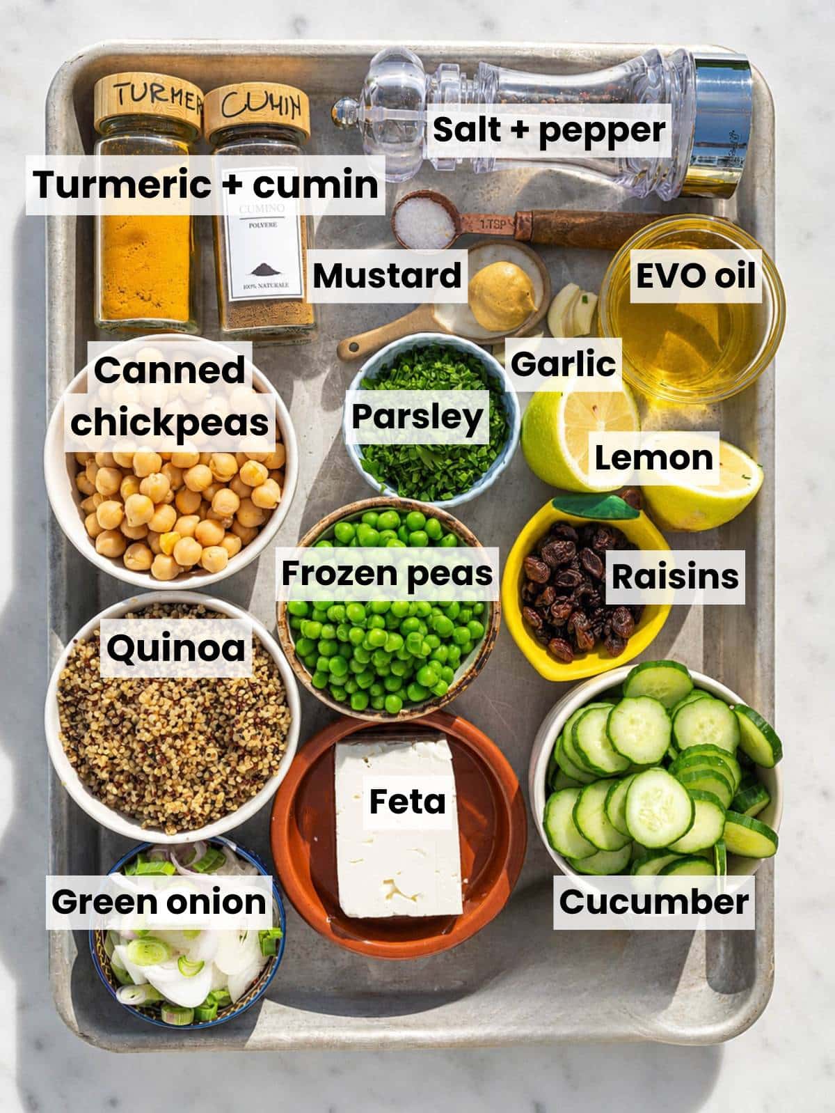 Ingredients for turmeric chickpea salad arranged in bowls on white marble countertop.