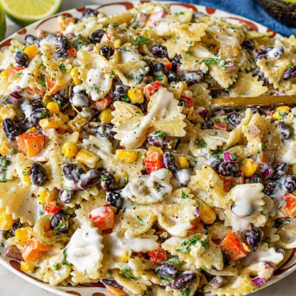 Mexican pasta salad in a white serving bowl on a marble countertop.