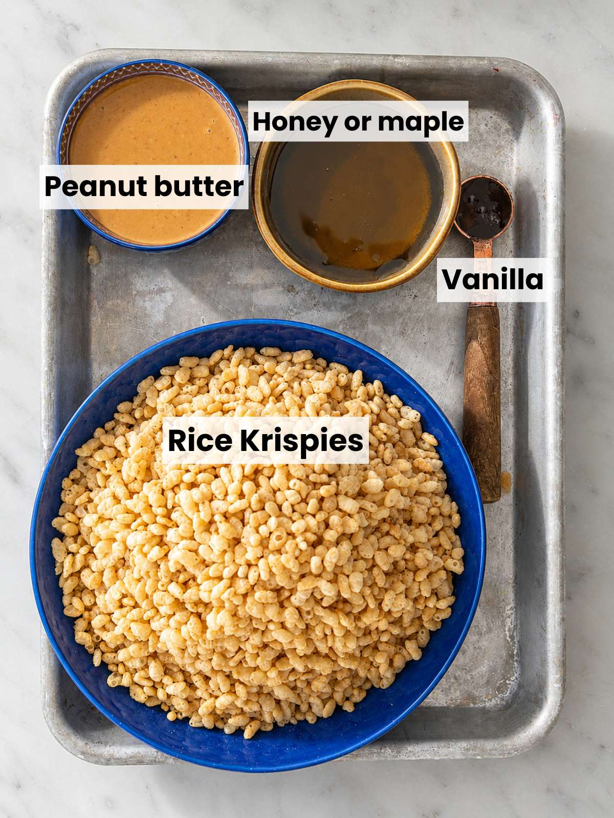 Rice Krispies, peanut butter, honey, and vanilla on white marble.