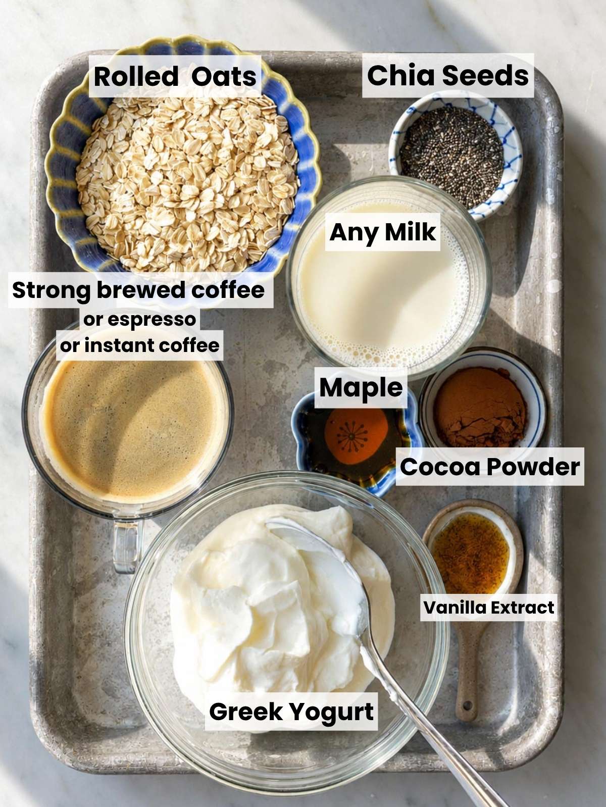 Rolled oats, coffee, yogurt, cocoa powder and other ingredients on a table.