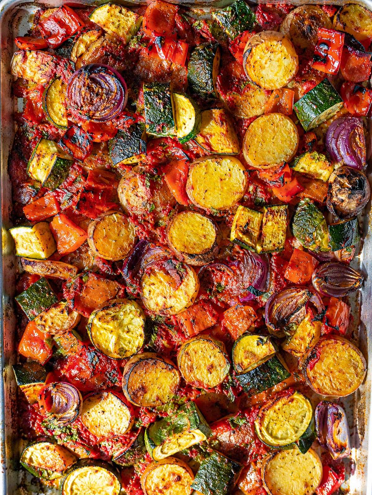 Sheet pan briam with roasted potatoes, zucchini, peppers, onions, and tomato sauce.