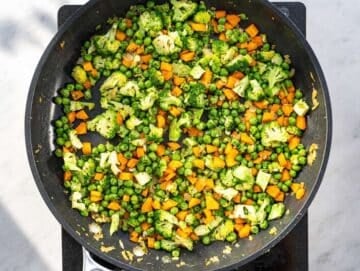 Step 2 Chopped onion, carrot, and broccoli sautéing in a hot skillet.