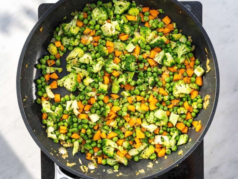 Step 2 Chopped onion, carrot, and broccoli sautéing in a hot skillet.