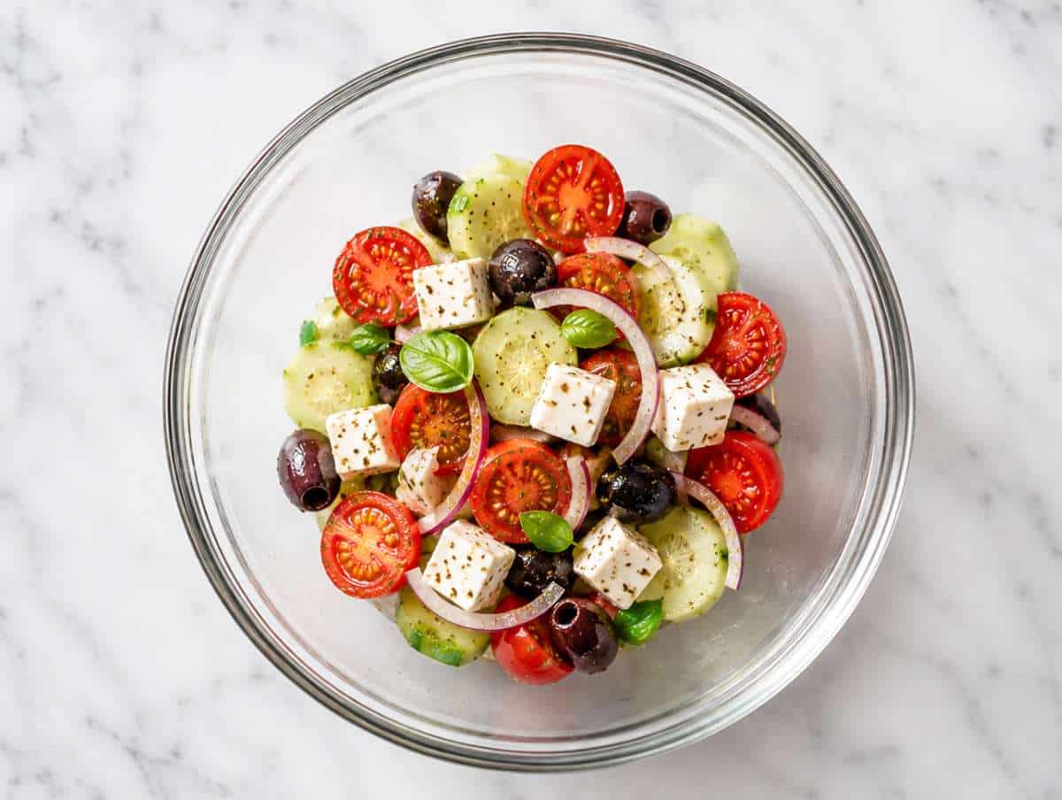 Step 3 Cucumber slices, cherry tomatoes, red onion, and Kalamata olives tossed with dressing