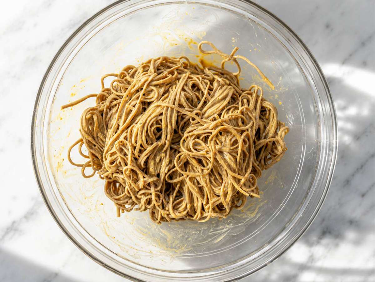 Step 3 Soba noodles tossed with creamy peanut dressing in bowl.