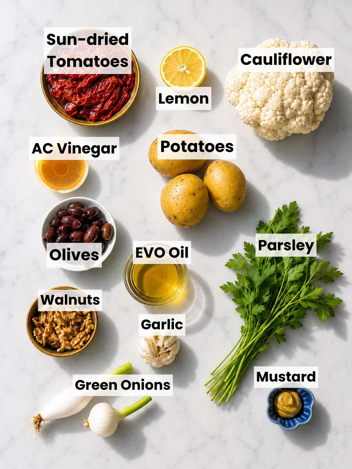 Whole cauliflower, potatoes, olives, walnuts, lemons, and herbs.