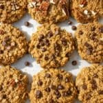 Banana peanut butter cookies with chocolate chips and pecans on parchment in bright daylight.