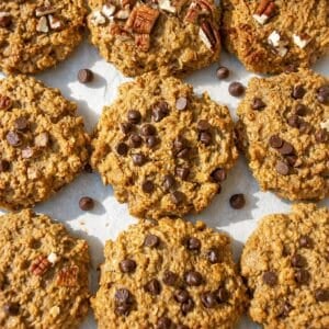 Banana peanut butter cookies with chocolate chips and pecans on parchment in bright daylight.