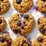 Blueberry oatmeal cookies on baking paper with blueberries in bright natural daylight.