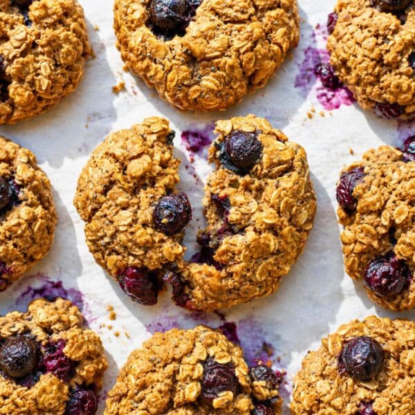 Blueberry oatmeal cookies on baking paper with blueberries in bright natural daylight.