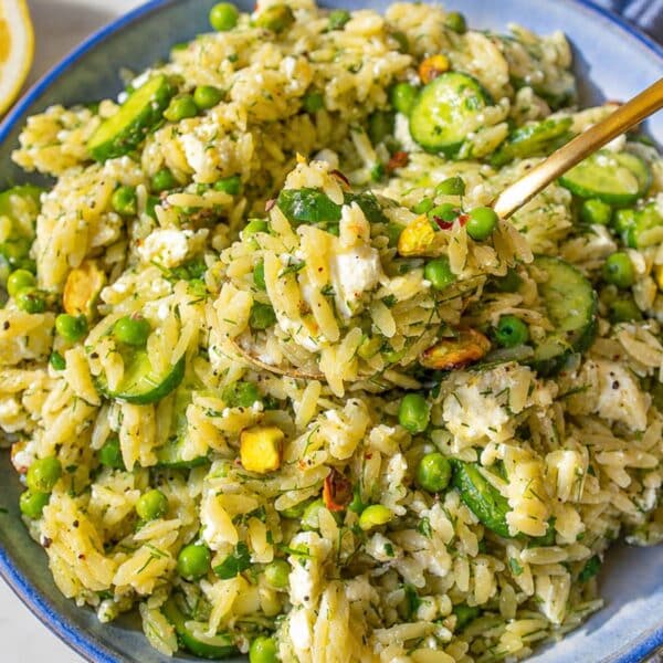 Bowl of lemon orzo salad with peas, feta, and fresh herbs.