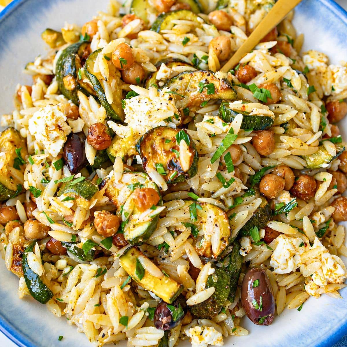 Bowl of roasted zucchini orzo beside a bright window.