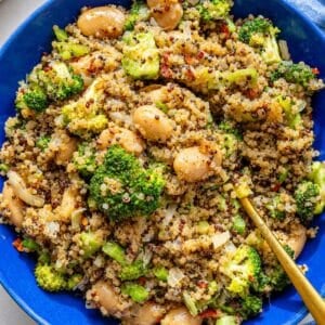 Broccoli quinoa skillet served in a blue bowl on white marble.