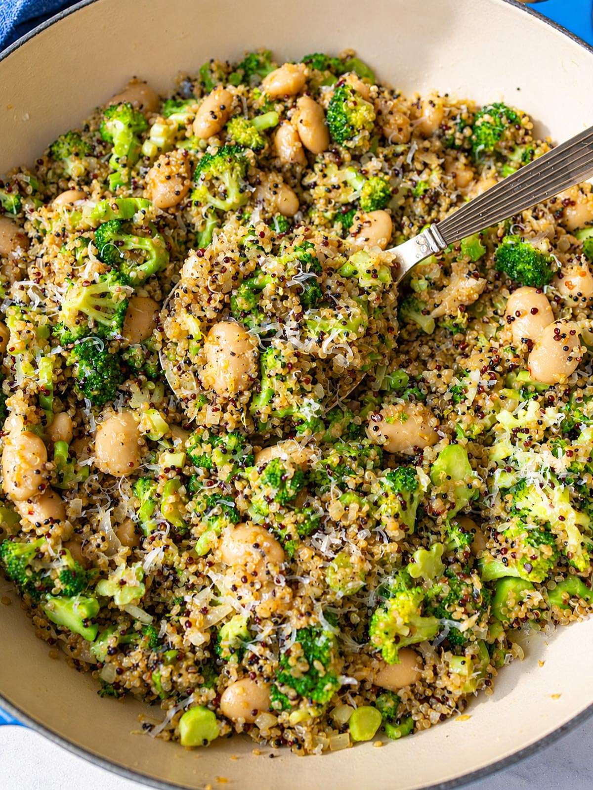 Broccoli quinoa skillet with butter beans, Parmesan, and lemon in natural daylight.