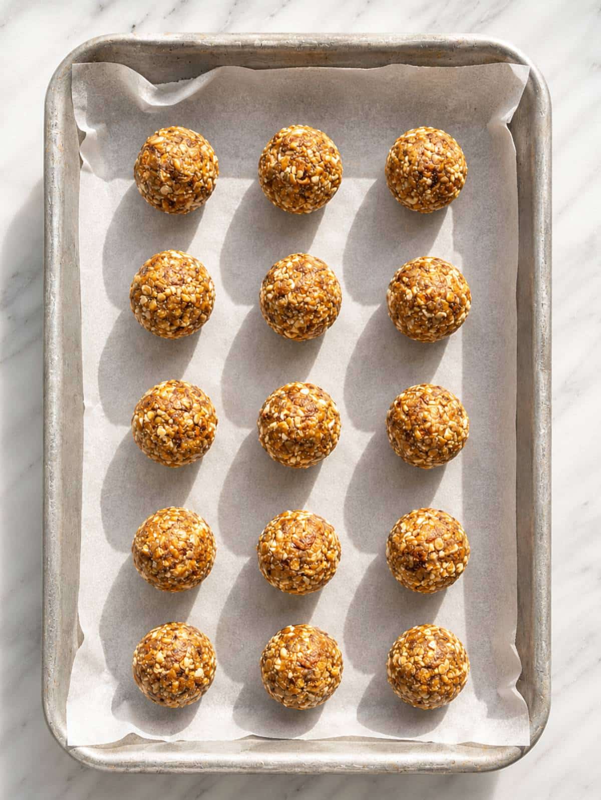Cashew energy balls after shaping on baking paper with natural light.