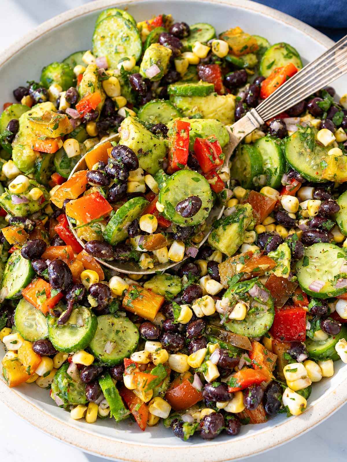 Chimichurri black bean salad with avocado in white bowl under natural window light.