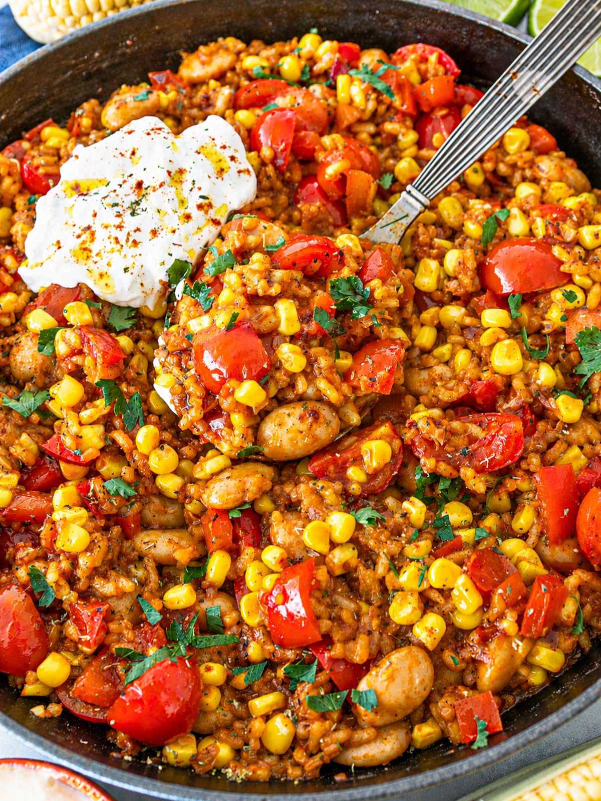 Close-up of glossy butter beans, charred corn, tomatoes, and textured rice grains.