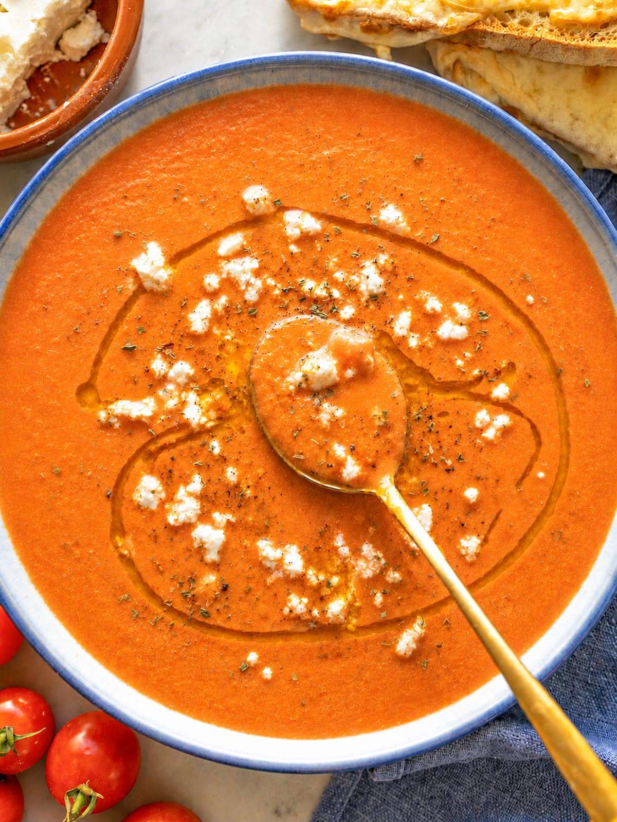 Creamy roasted tomato soup topped with feta, basil, and olive oil.
