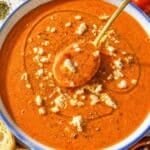 Creamy roasted tomato soup with toasted bread on white marble countertop.
