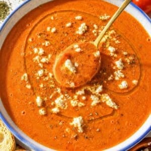 Creamy roasted tomato soup with toasted bread on white marble countertop.