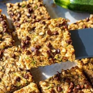 Freshly baked zucchini banana bars sliced on parchment over white marble countertop.