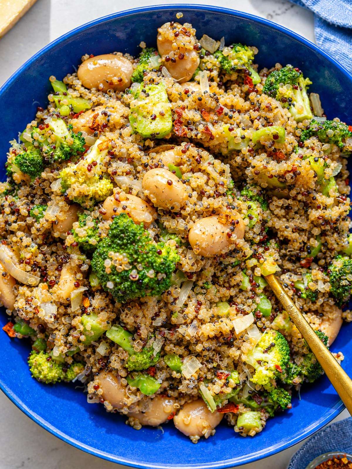 Glossy butter beans, toasted quinoa, and browned broccoli with Parmesan in a bowl.